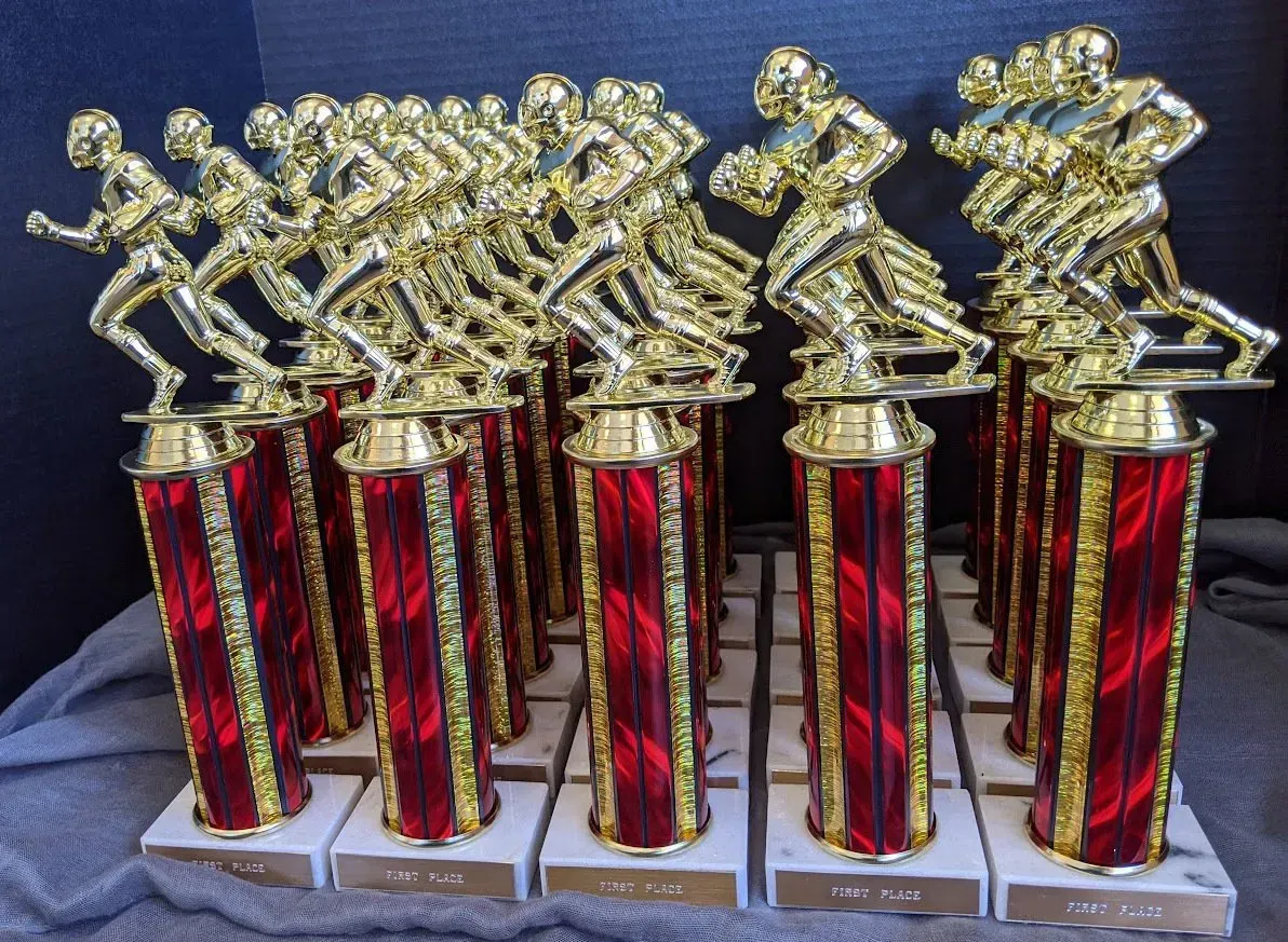 A bunch of red and gold trophies on a table
