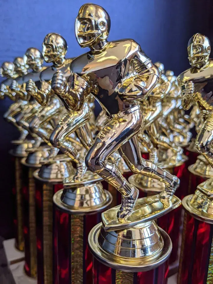 A row of trophies with a football player on top of them.