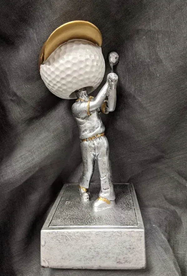 A statue of a man swinging a golf club with a golf ball on his head.