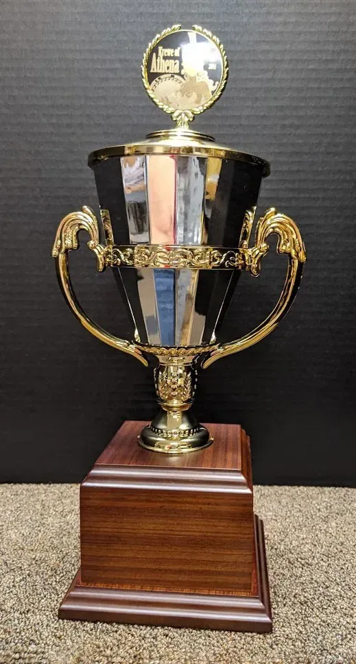 A trophy is sitting on top of a wooden base on a carpet.