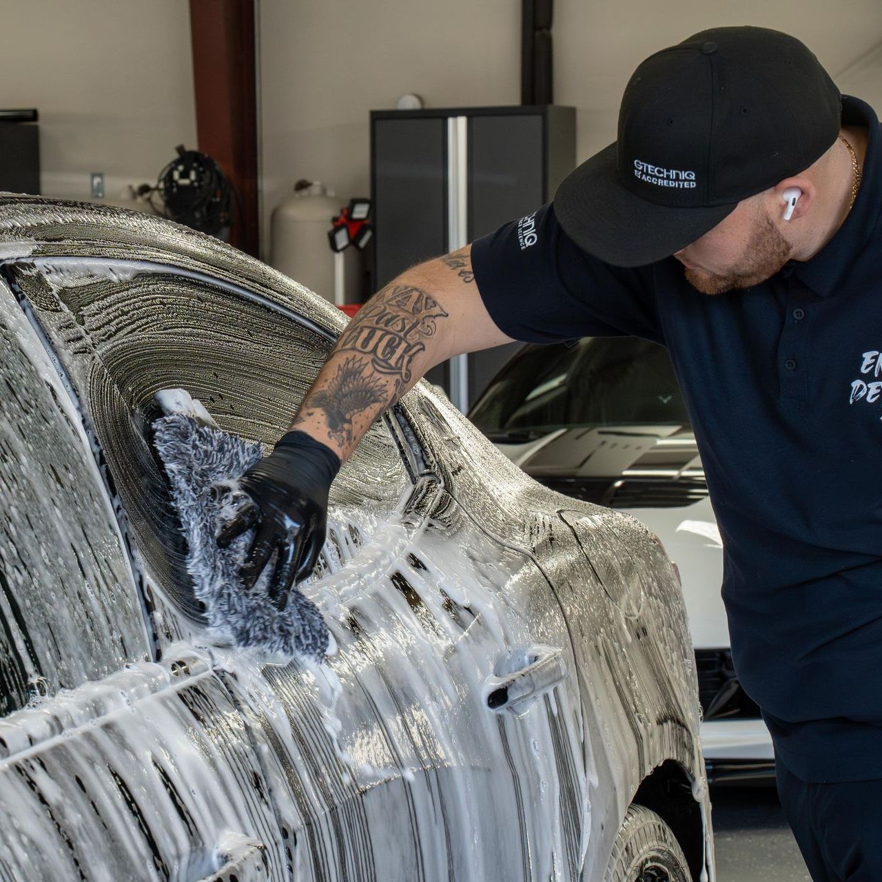 A person is cleaning a black car with a cloth.