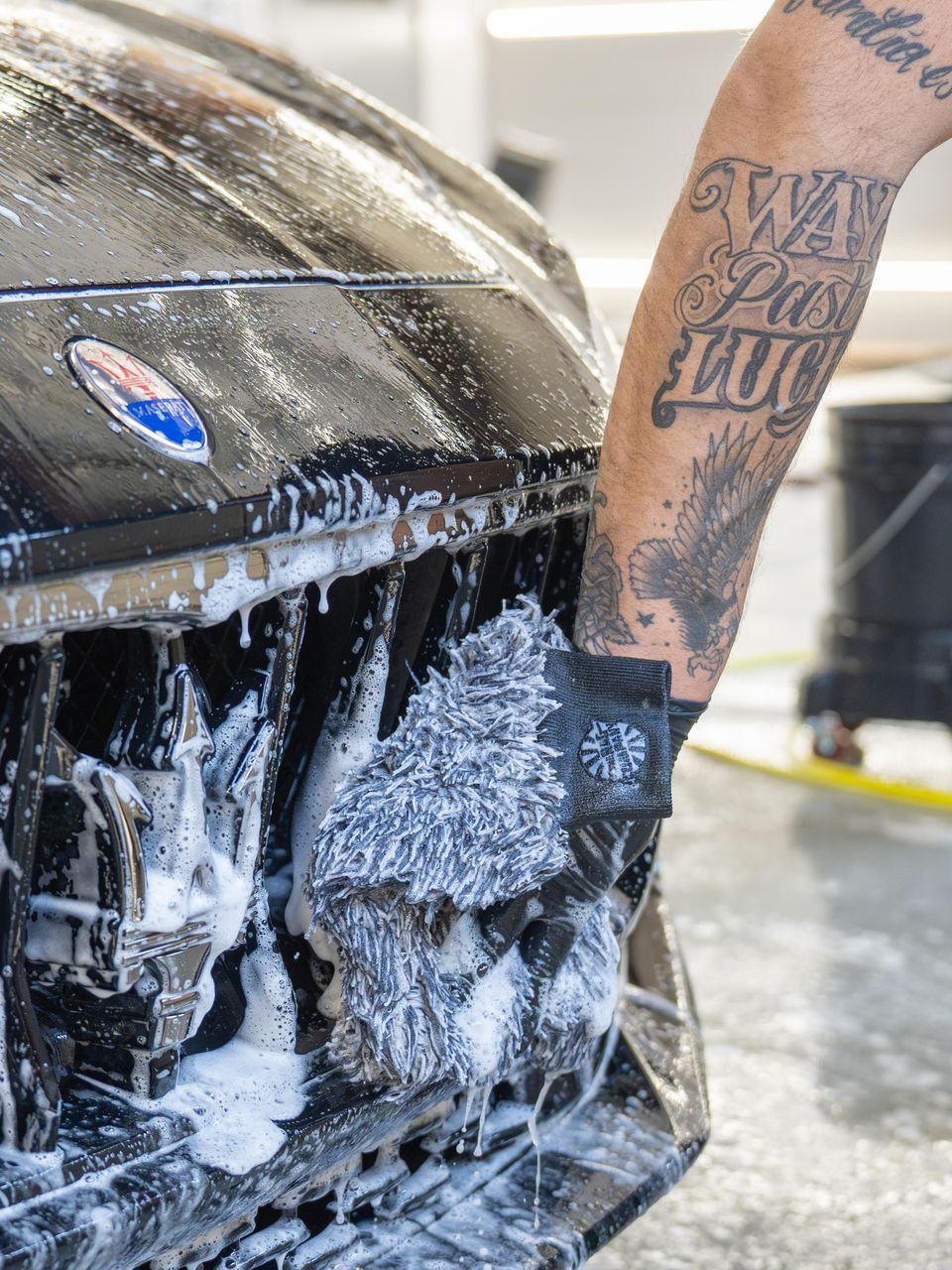 A person is washing a car with a sponge and soap.