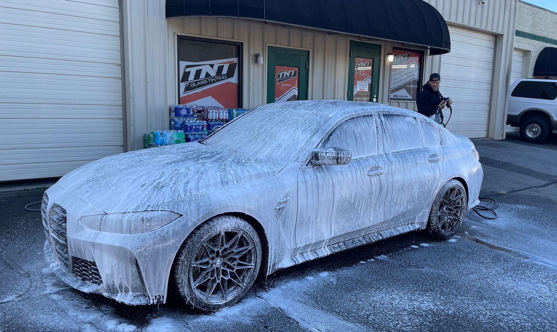 A car is covered in foam in front of a building.