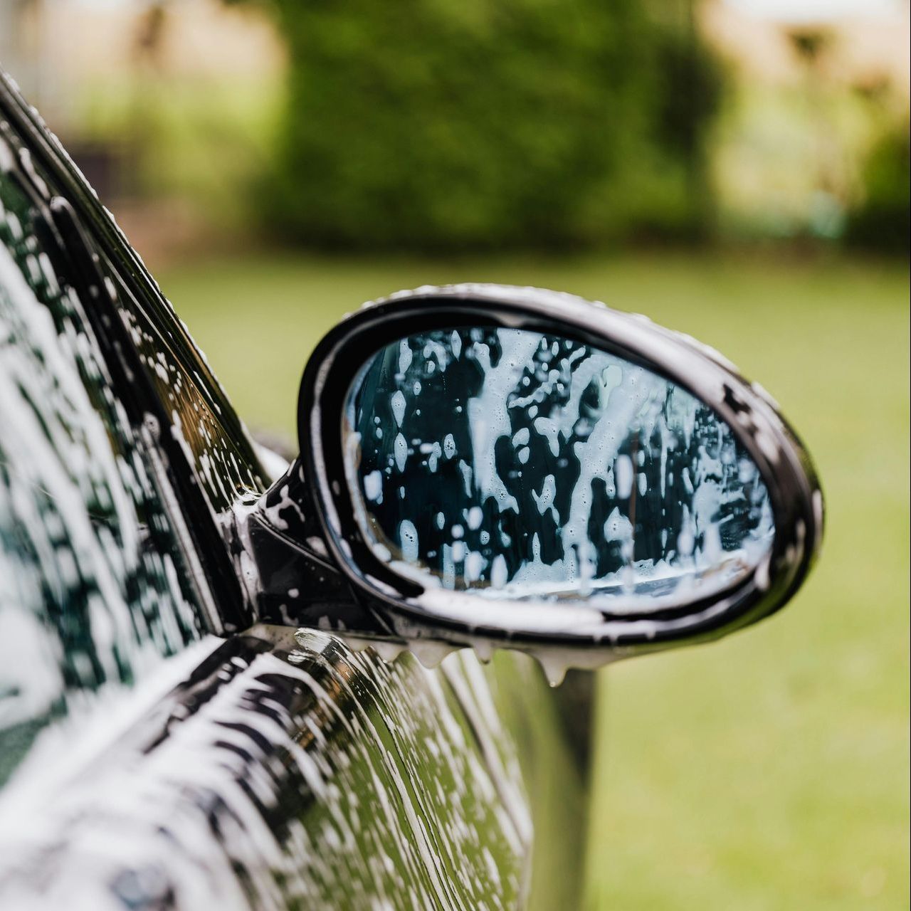 A close up of a car 's side mirror covered in soap