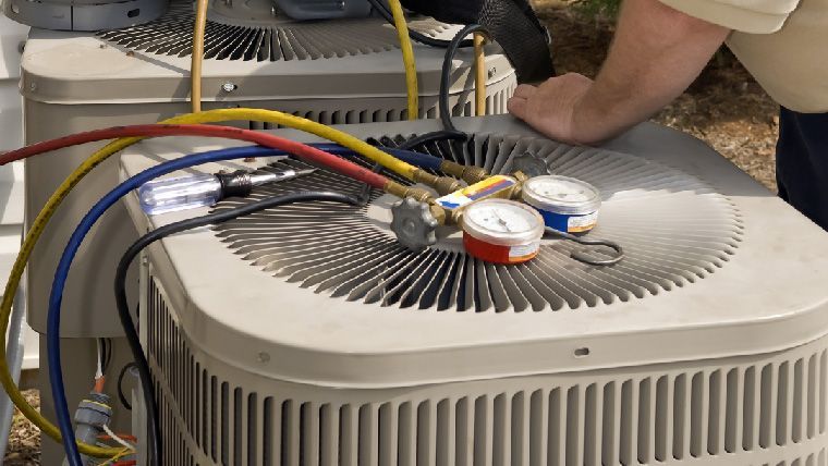 A man is working on an air conditioner with hose attached to it.