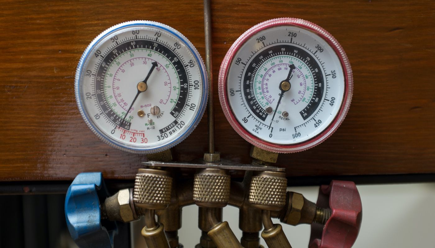 Two pressure gauges are hanging on a wooden wall.