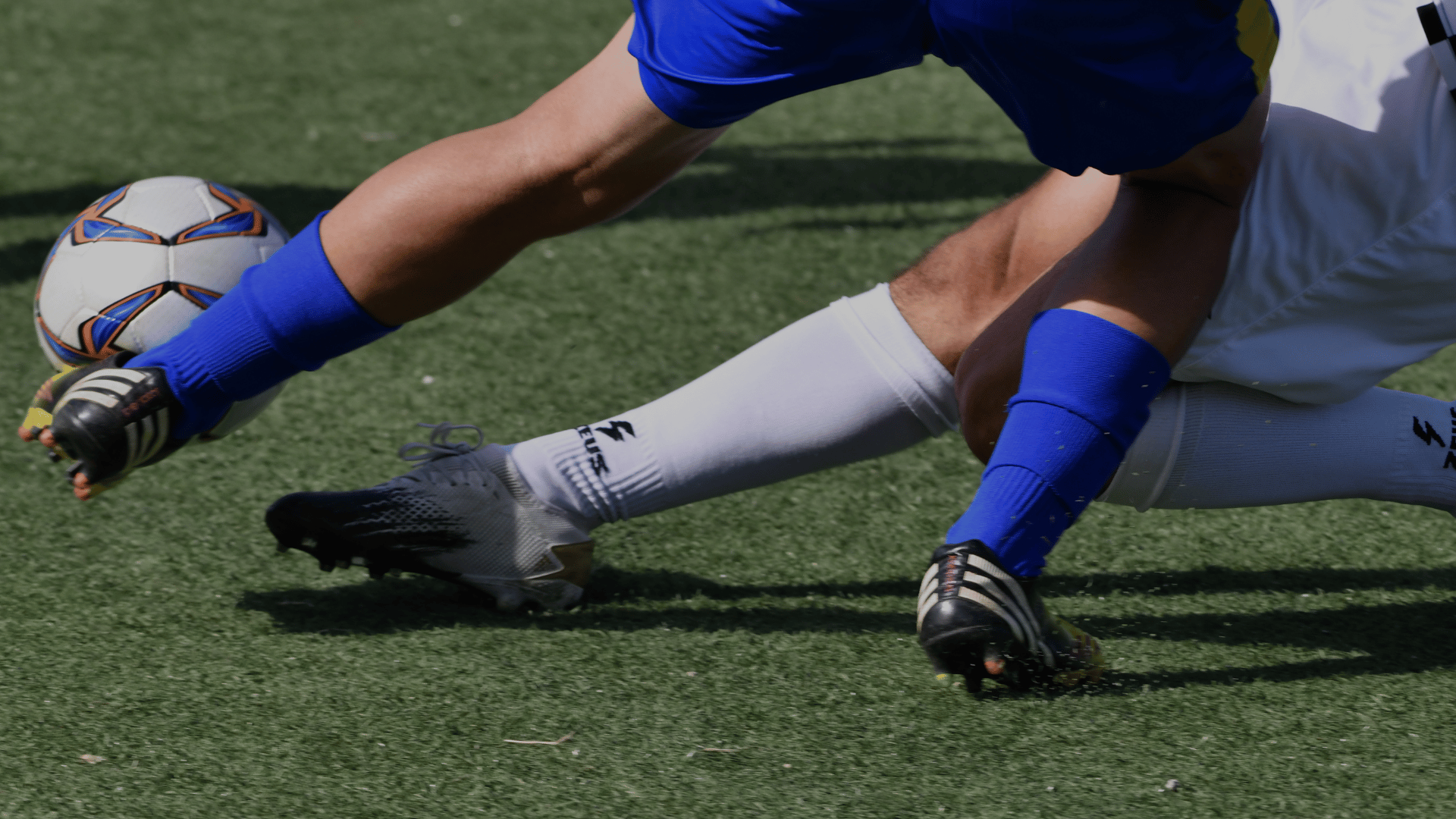 Two soccer players are playing a game of soccer on a field.