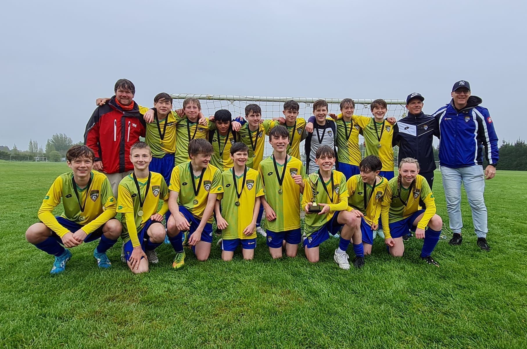 A group of young boys are posing for a picture on a soccer field.