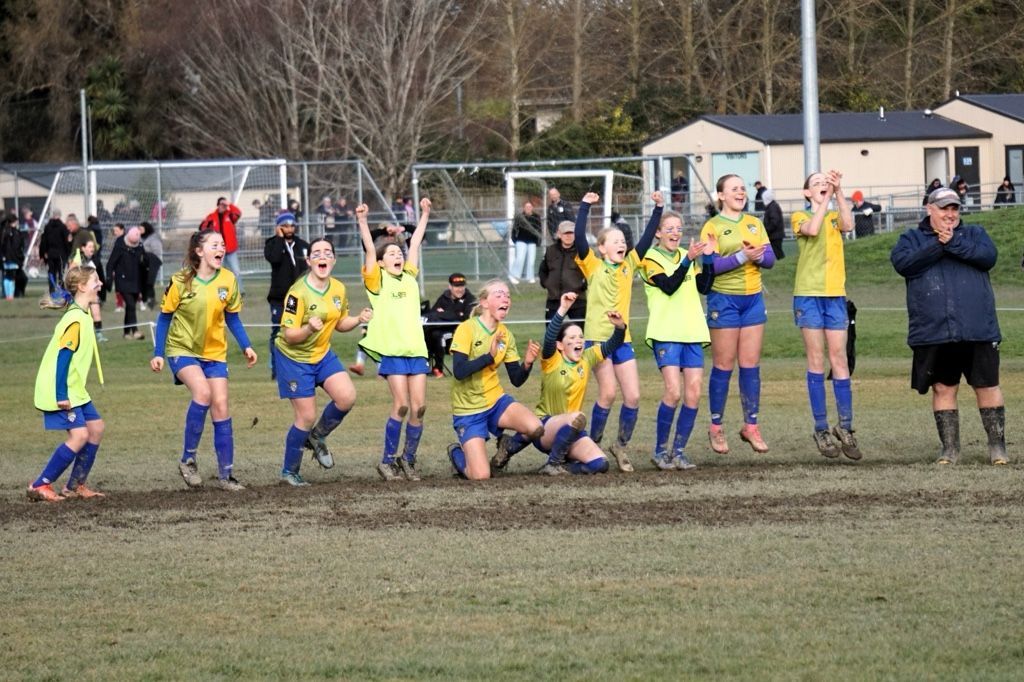 Two women are playing soccer and one is wearing a yellow shirt
