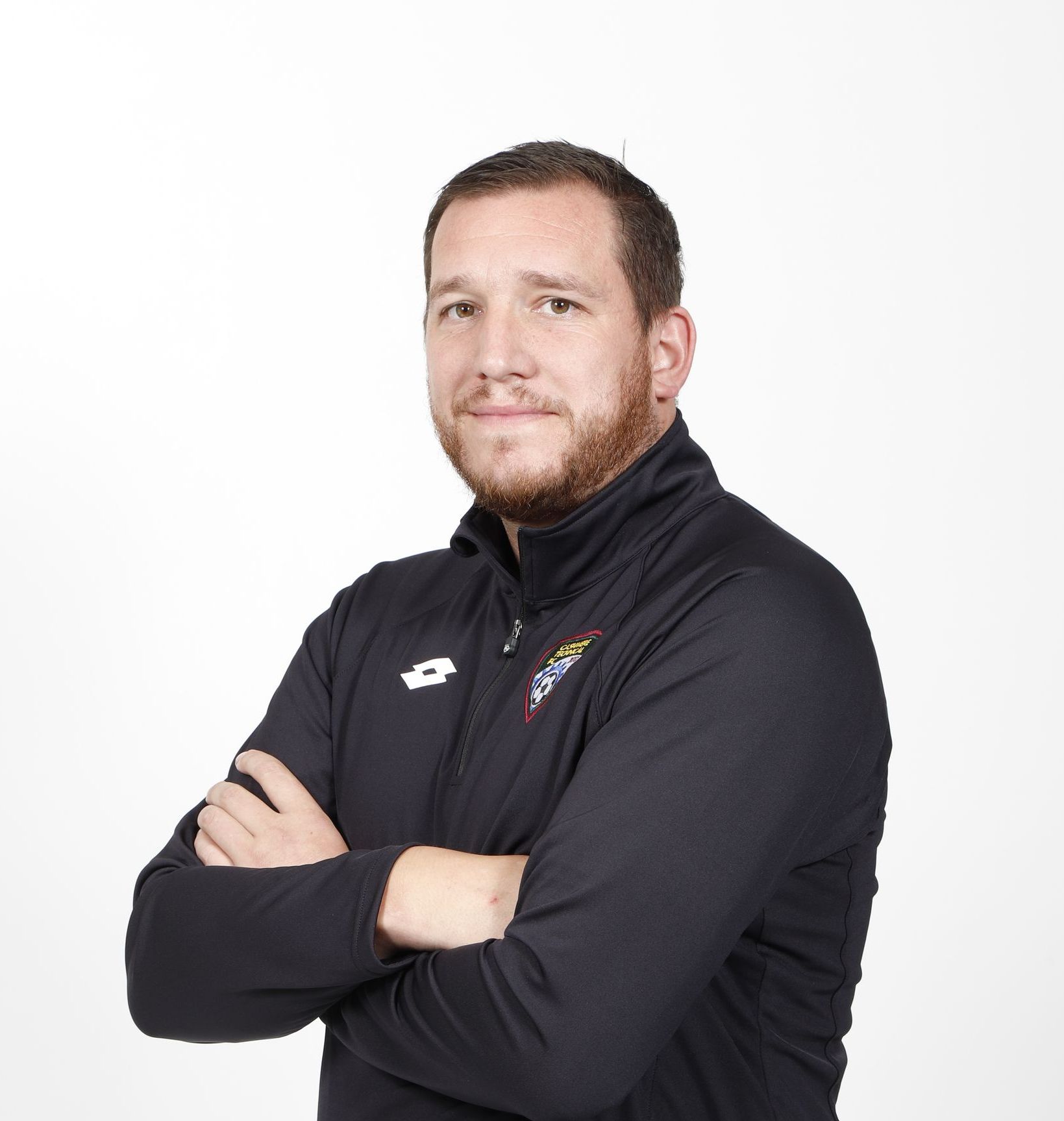 A young man is smiling and wearing a brown shirt.