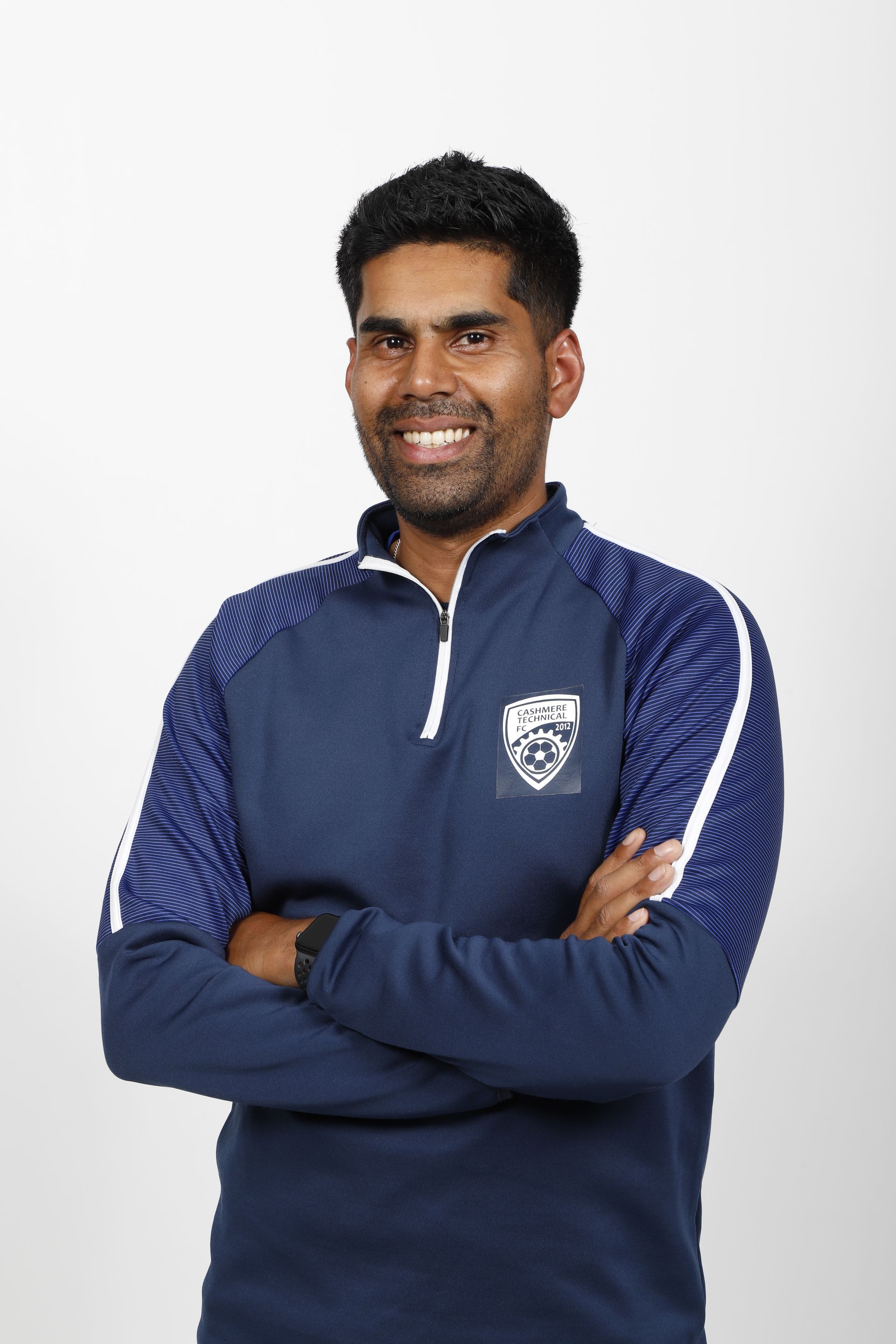 A young man is smiling and wearing a brown shirt.