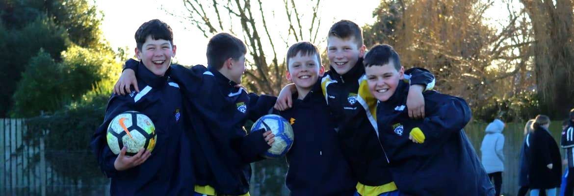 A group of young boys are posing for a picture while holding soccer balls.