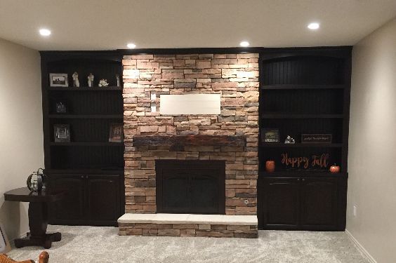 A living room with a fireplace and shelves.