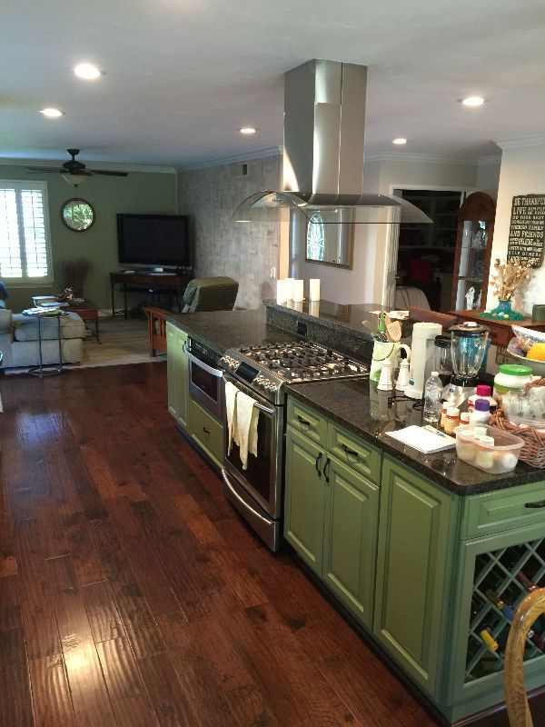 A kitchen with green cabinets and a stove top oven