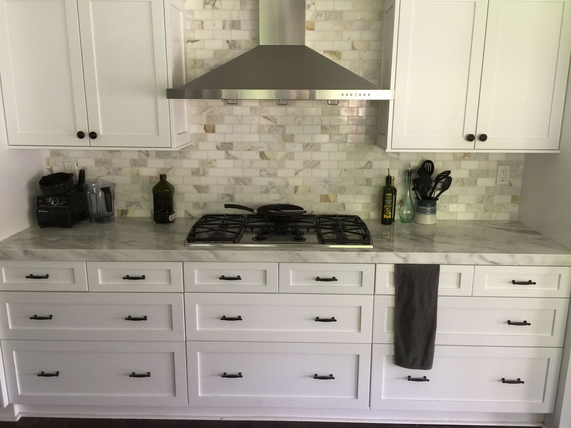 A kitchen with white cabinets and a stove top oven