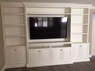 A white entertainment center with a flat screen tv and shelves