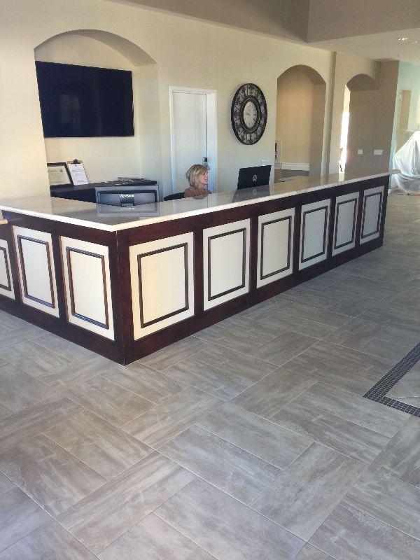 A woman sits at a long reception desk in a room