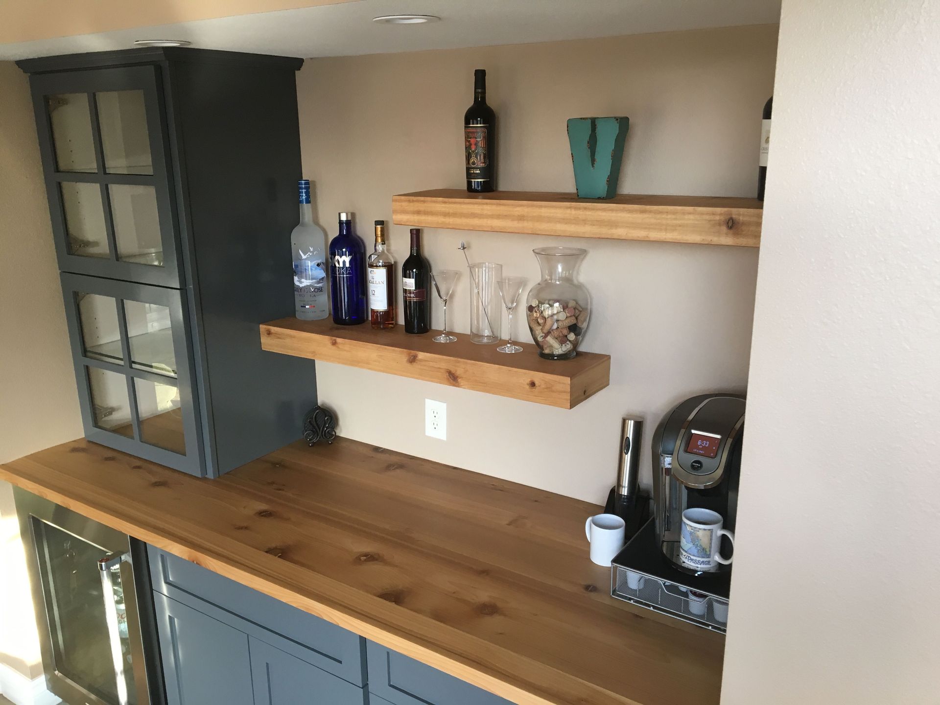 A kitchen with a wooden counter top and bottles on shelves