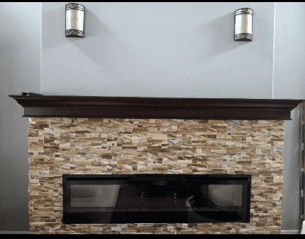 A fireplace with a stone wall and a wooden mantle