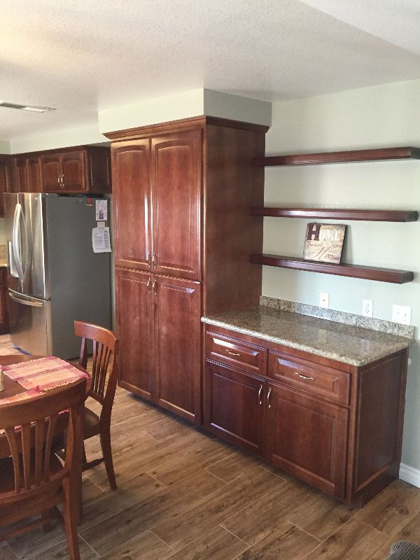 A kitchen with wooden cabinets , a refrigerator , a table and chairs