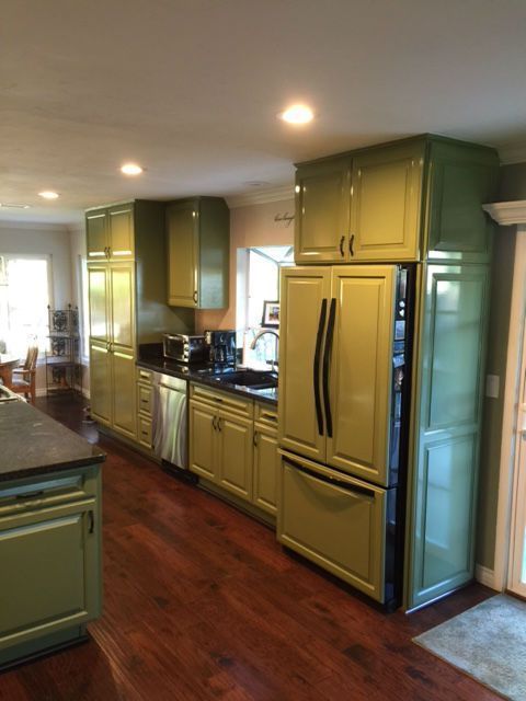 A kitchen with green cabinets and a black refrigerator