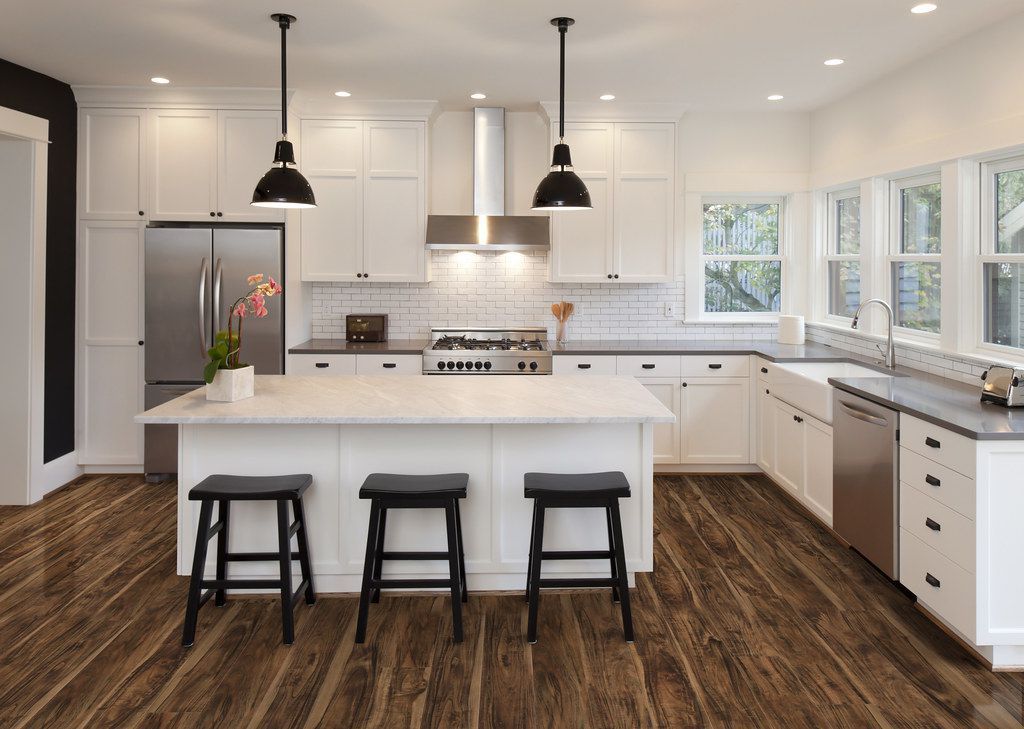 A kitchen with white cabinets , stainless steel appliances , and hardwood floors