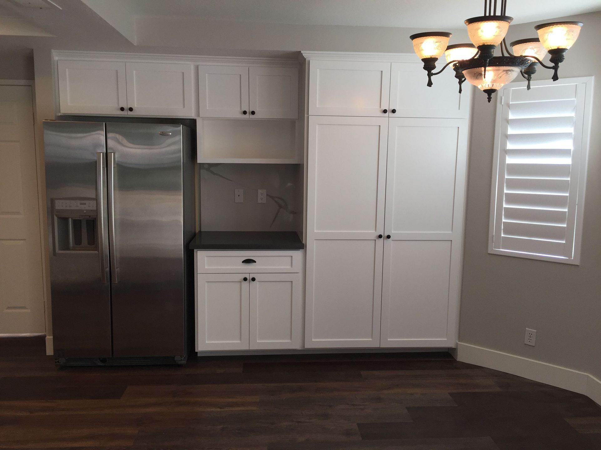A kitchen with white cabinets and a stainless steel refrigerator