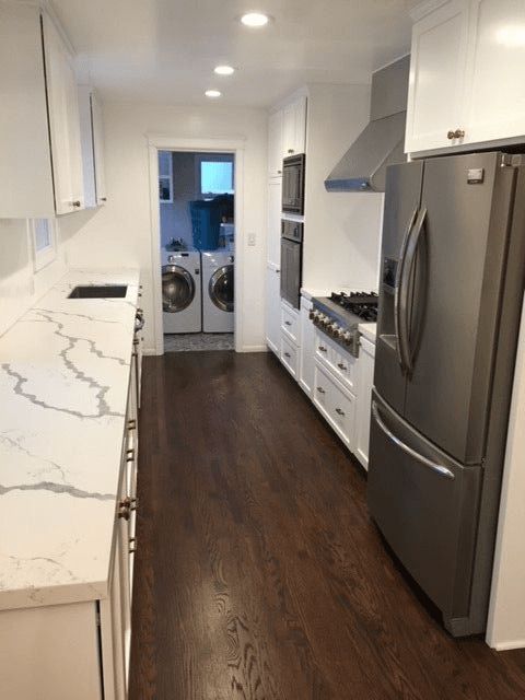 A kitchen with white cabinets and a black refrigerator