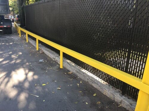 Yellow guard rail beside a fence—Security Fence in Bronx, NY