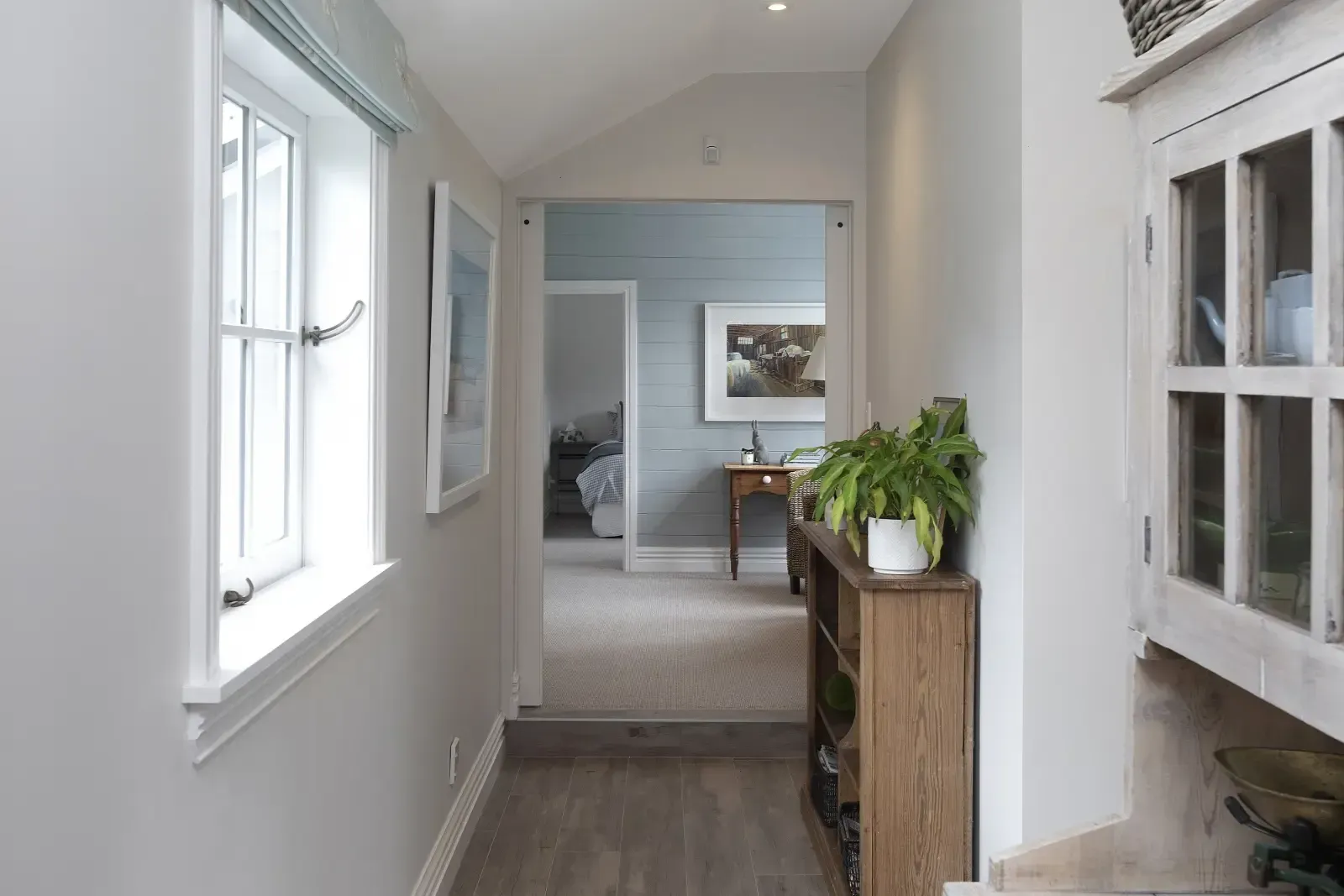 A hallway in a house with a wooden shelf in the middle of it.