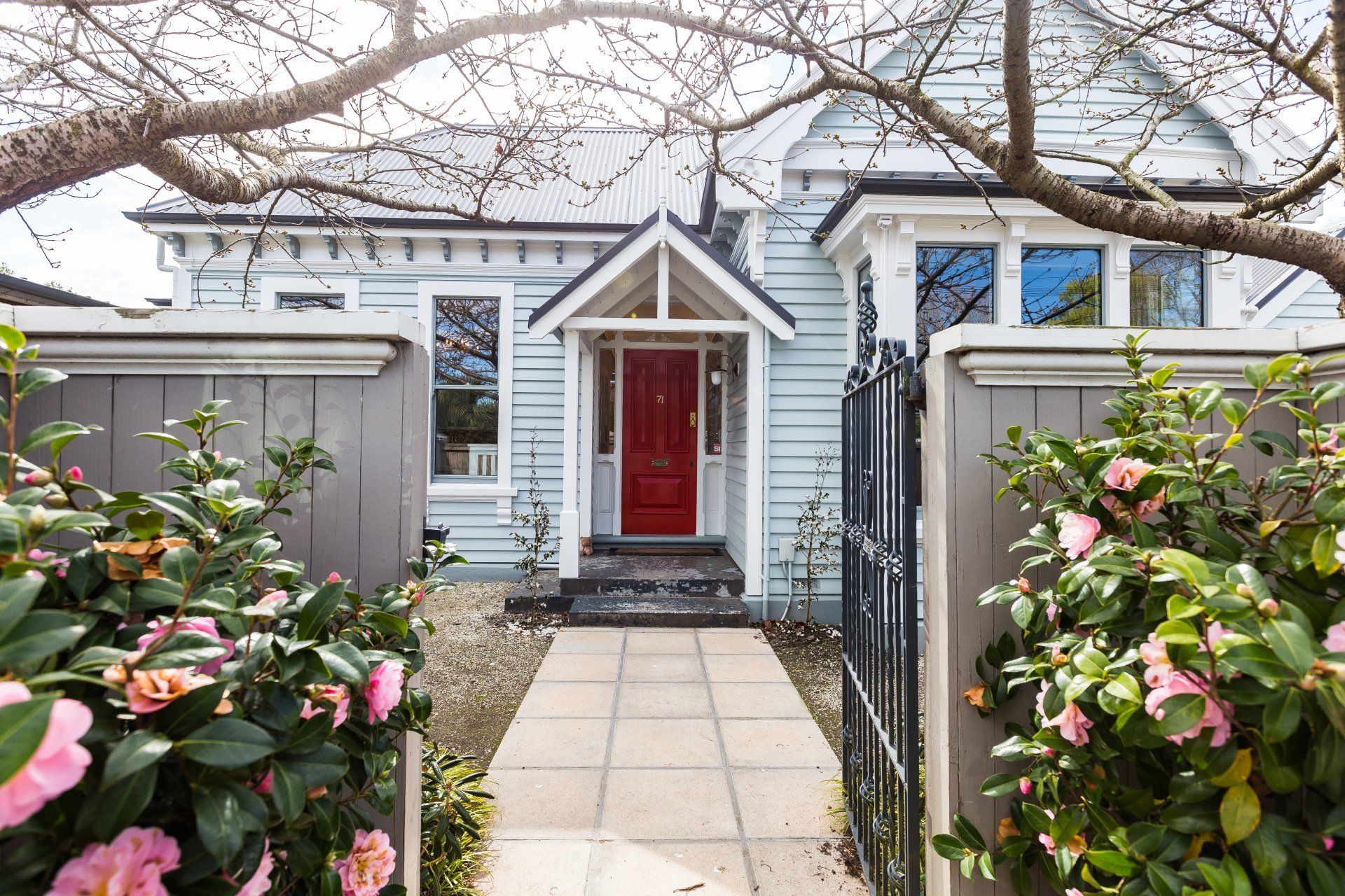 A blue house with a red door and a walkway leading to it.
