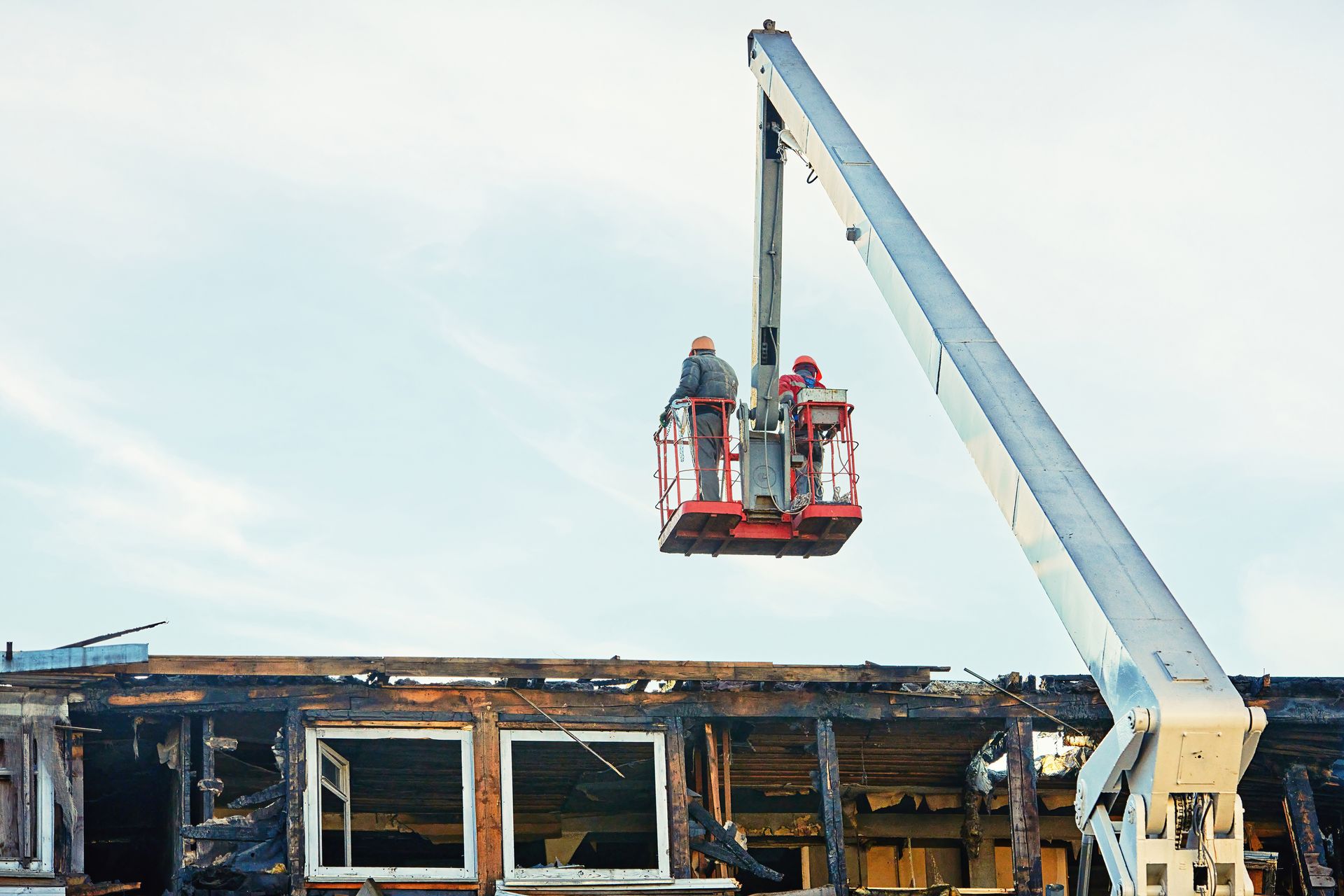 Workers in a lift inspecting a damaged building after a fire.