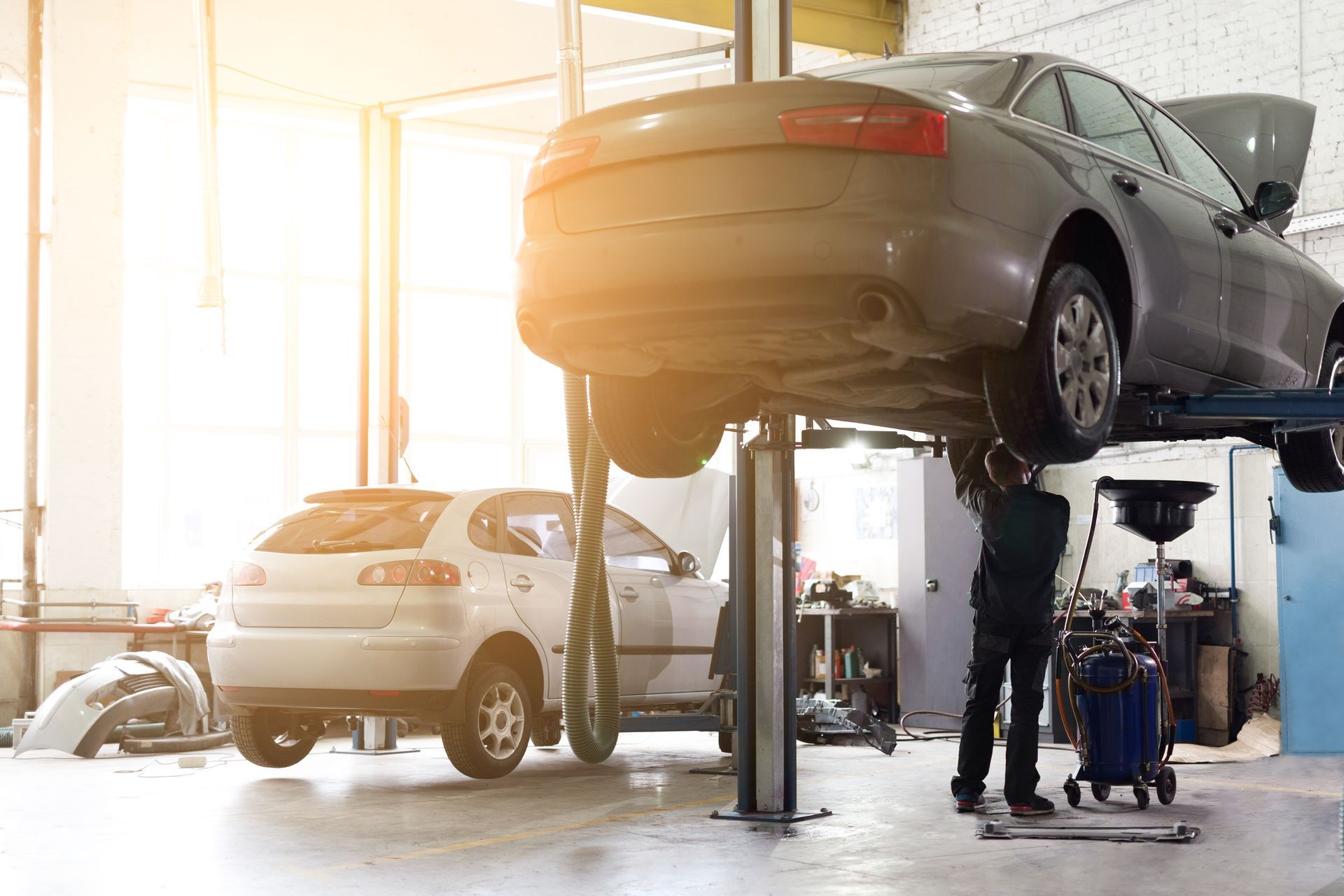 Cars on Lifts in an Auto Repair Shop, With Mechanics Working Underneath — Forster Smash Repairs in Forster, NSW