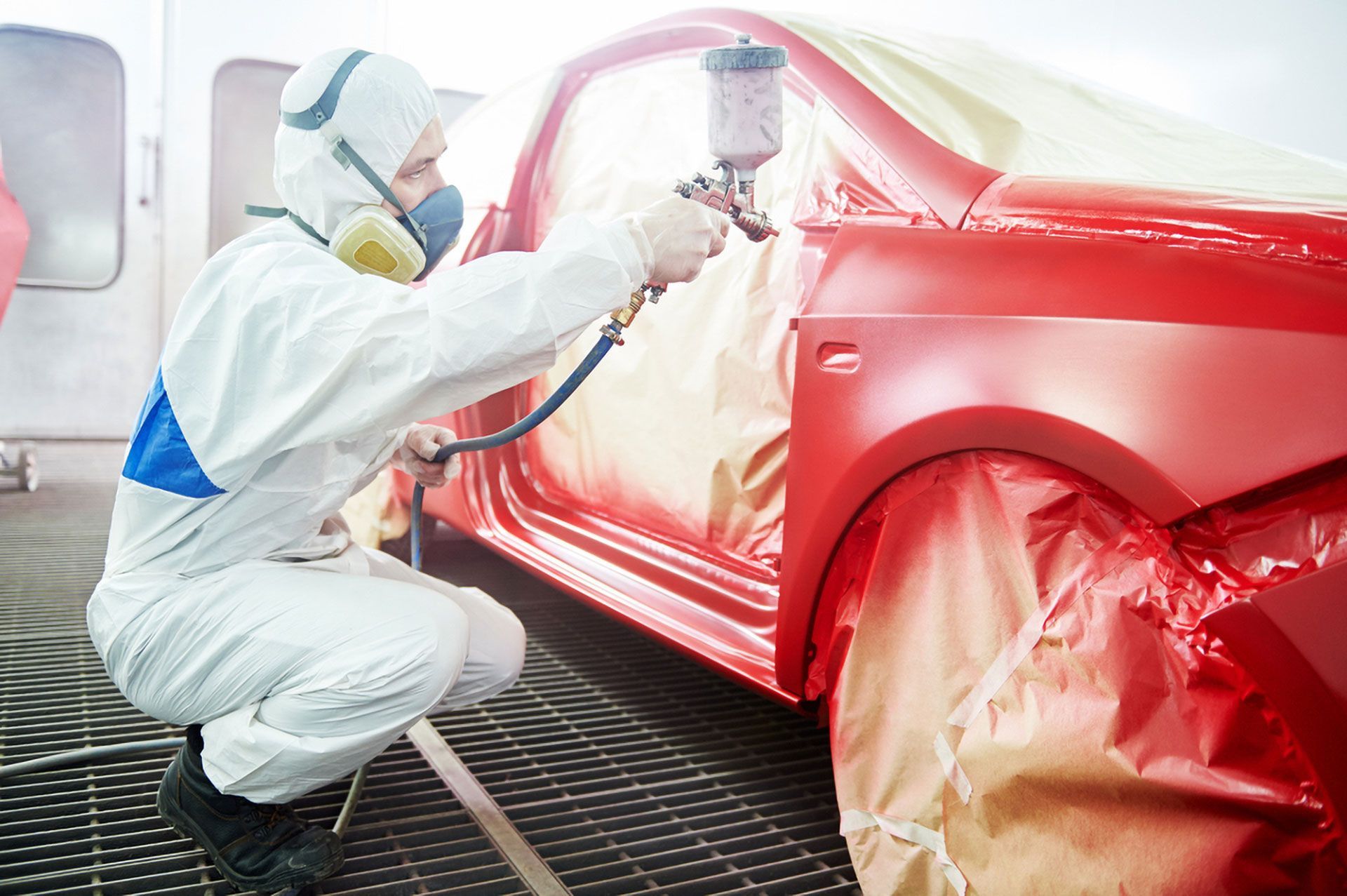 Technician Spray-painting a Red Car in a Paint Booth — Forster Smash Repairs in Forster, NSW