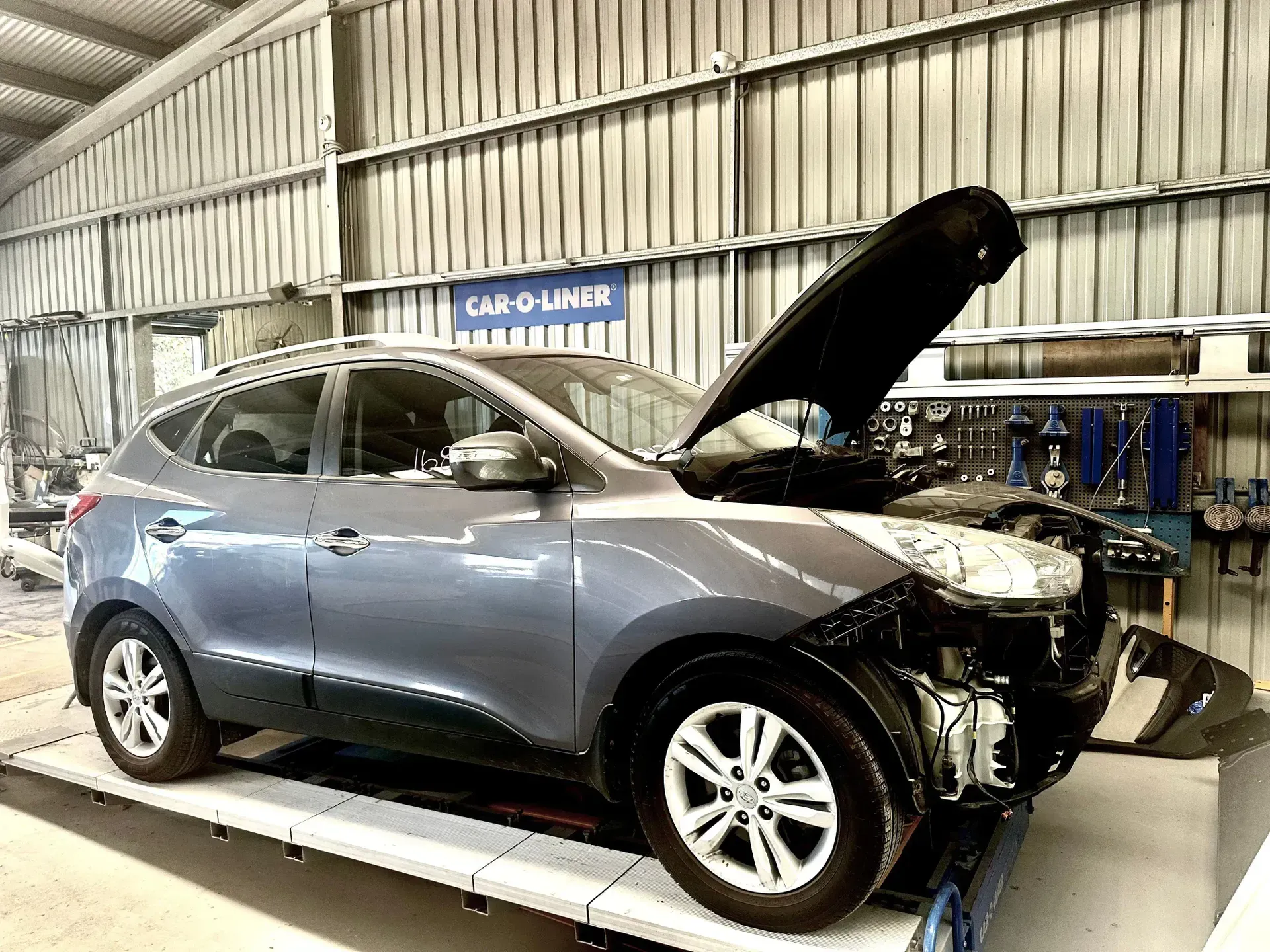 Damaged Gray SUV With Hood Open in a Repair Garage, Front End Damaged and Exposed — Forster Smash Repairs in Forster, NSW