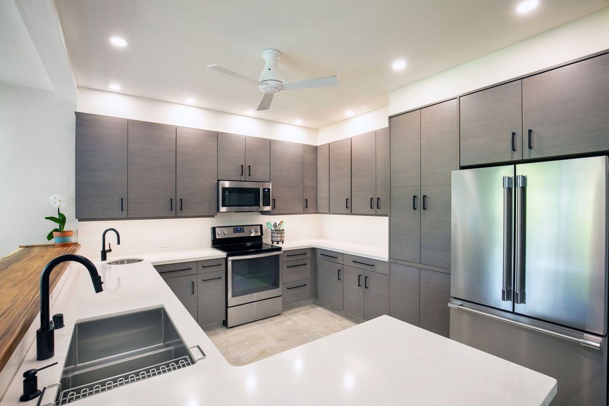 Modern gray kitchen with stainless steel appliances, white countertops, and wood accents.
