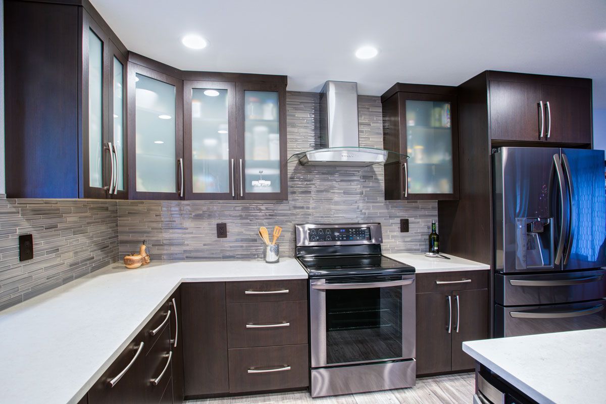 Modern kitchen with dark brown cabinets, stainless steel appliances, and white countertops.