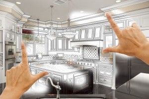 Hands framing a sketch of a kitchen with cabinets, stove, and island.