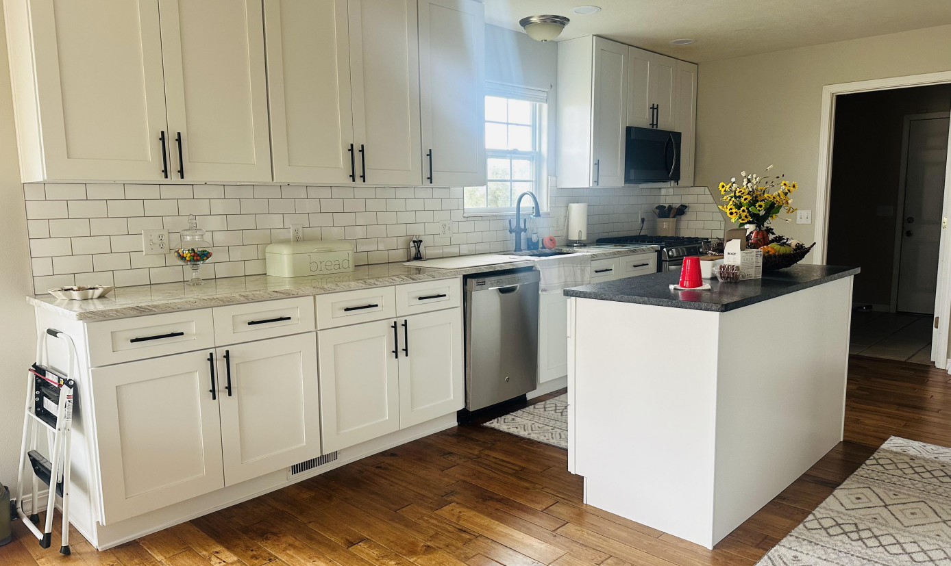Kitchen under construction with white cabinets, light wood countertops, and bare floor.