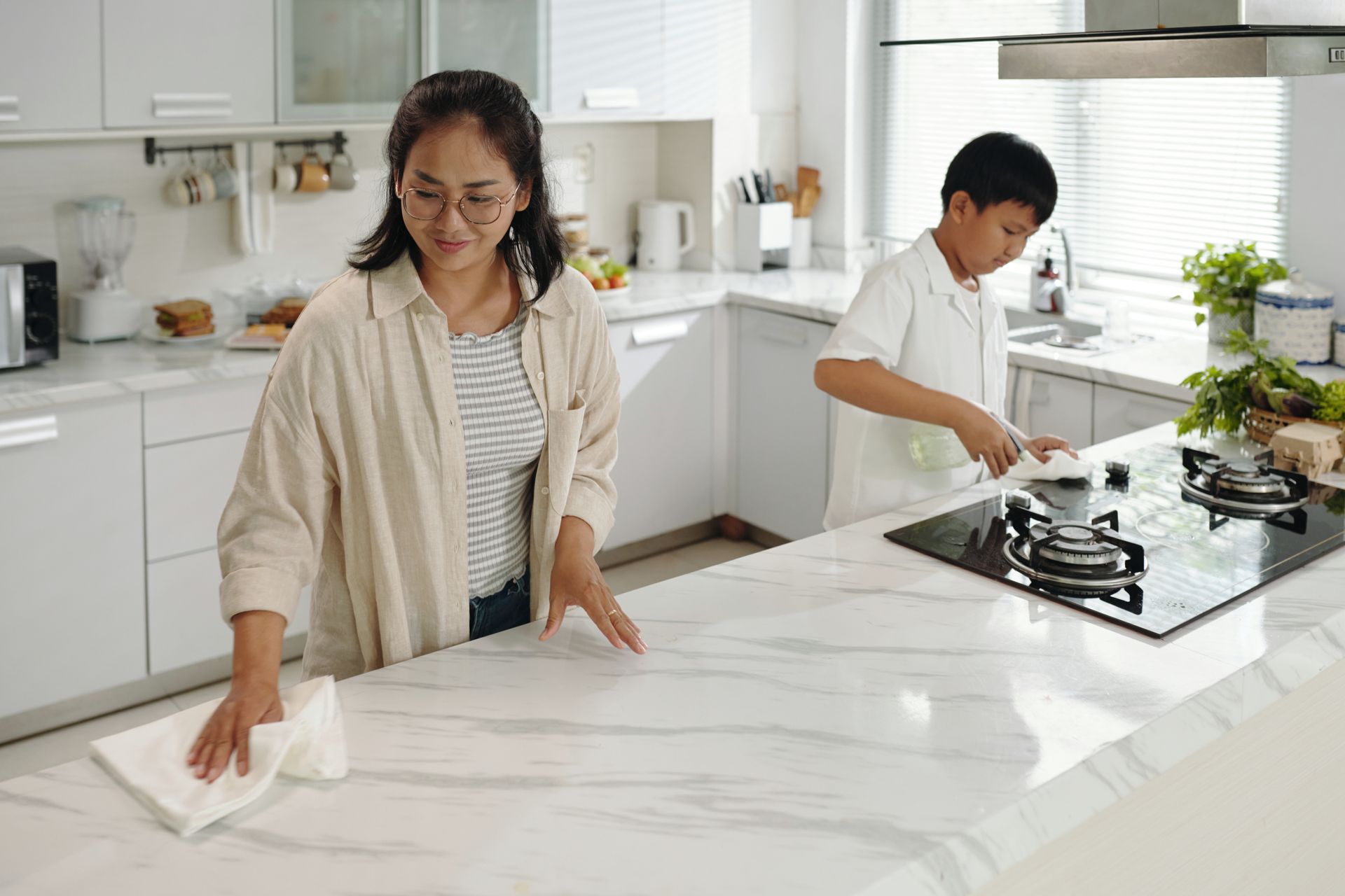 A woman and a boy are cleaning a kitchen counter.