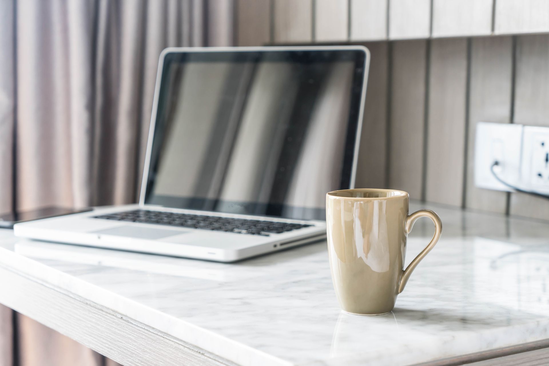 A laptop computer is sitting on a desk next to a cup of coffee.