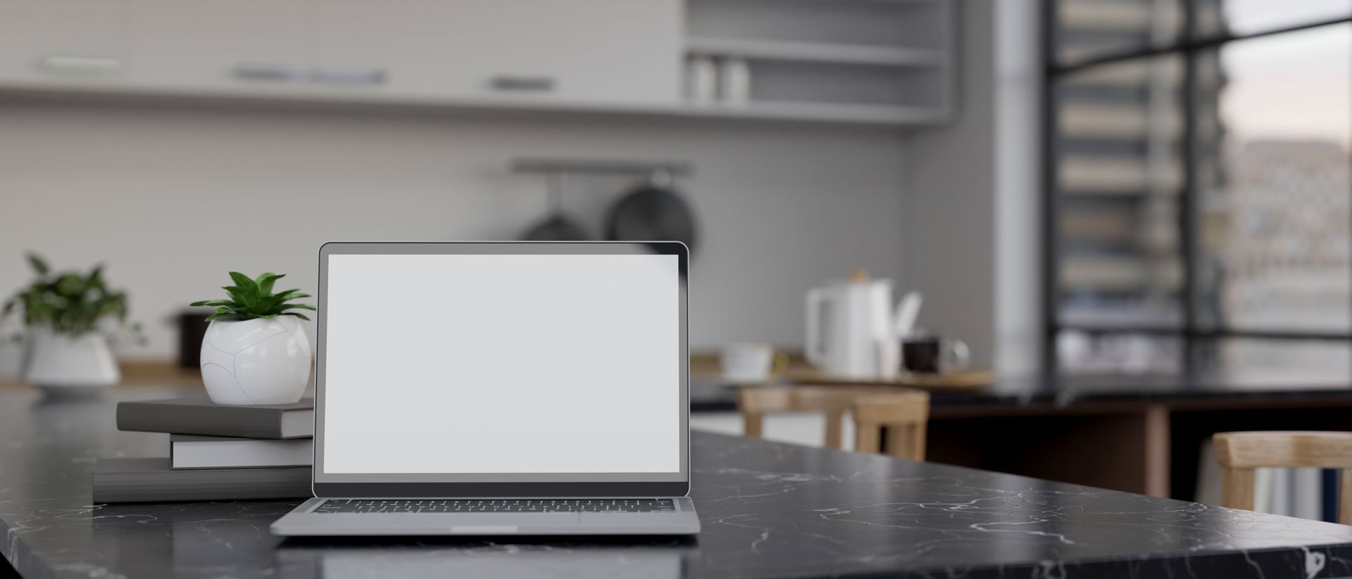 A laptop computer is sitting on a counter in a kitchen.