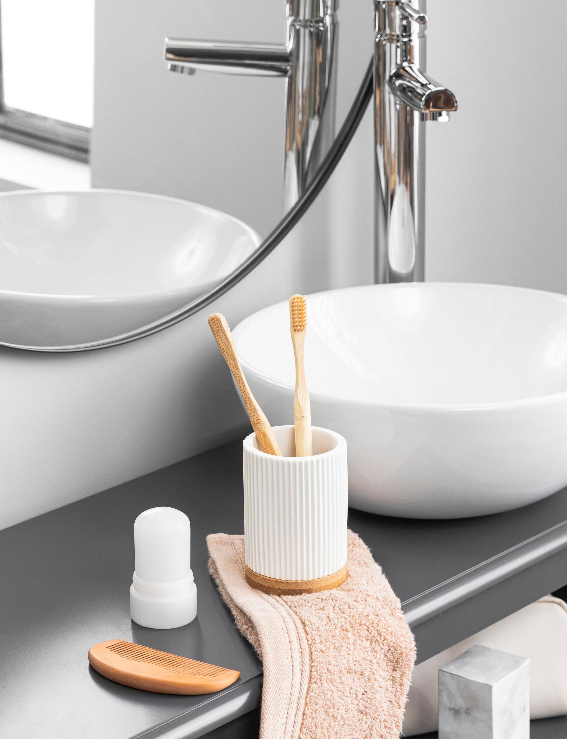 A bathroom sink with a toothbrush and comb in it.