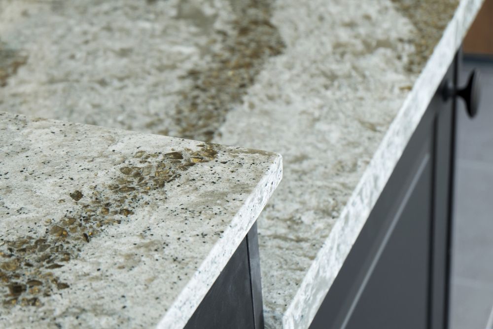 Close-up of granite countertop edge with black cabinets. Light and dark speckled patterns on the surface.