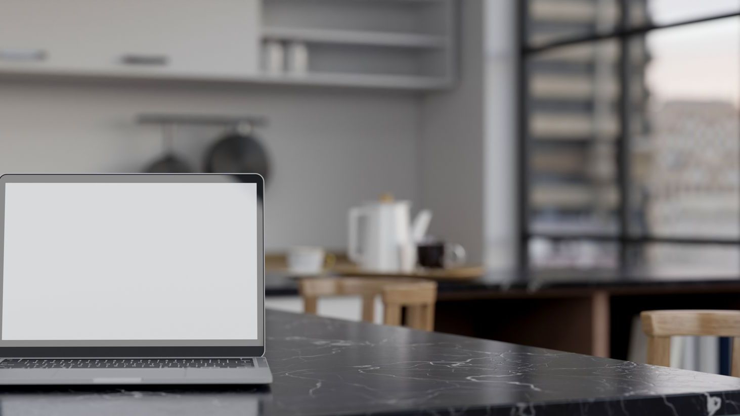 A laptop computer is sitting on a counter in a kitchen.