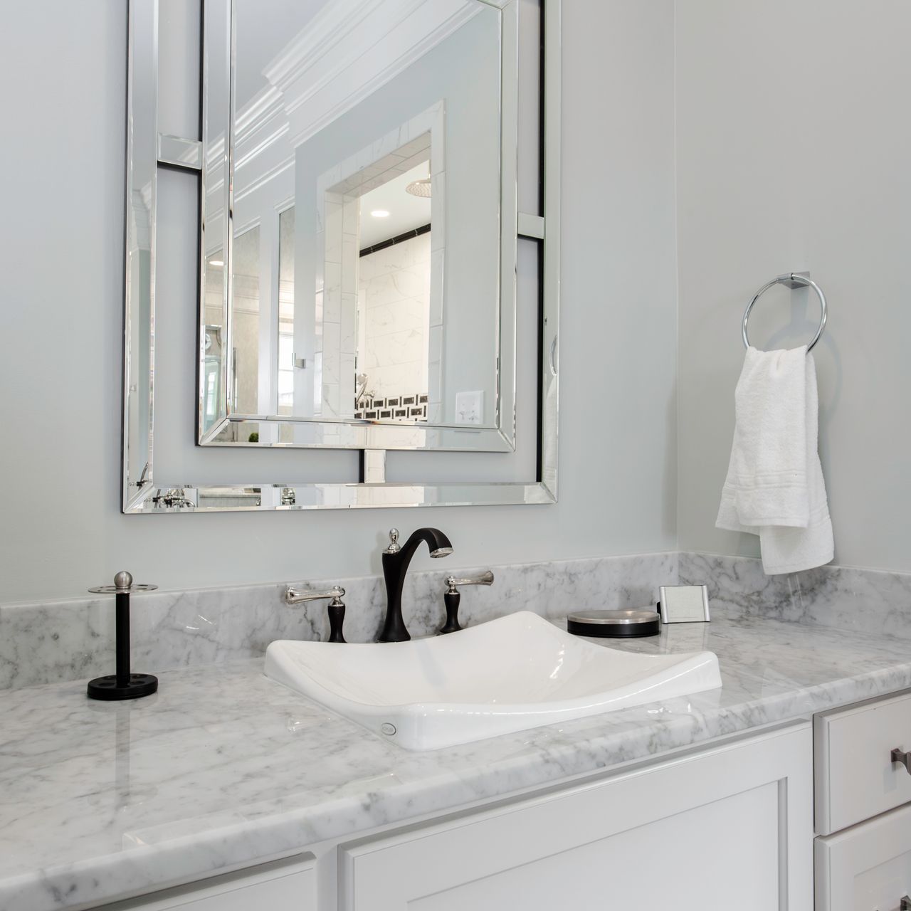 A bathroom with a sink , mirror and towel rack.