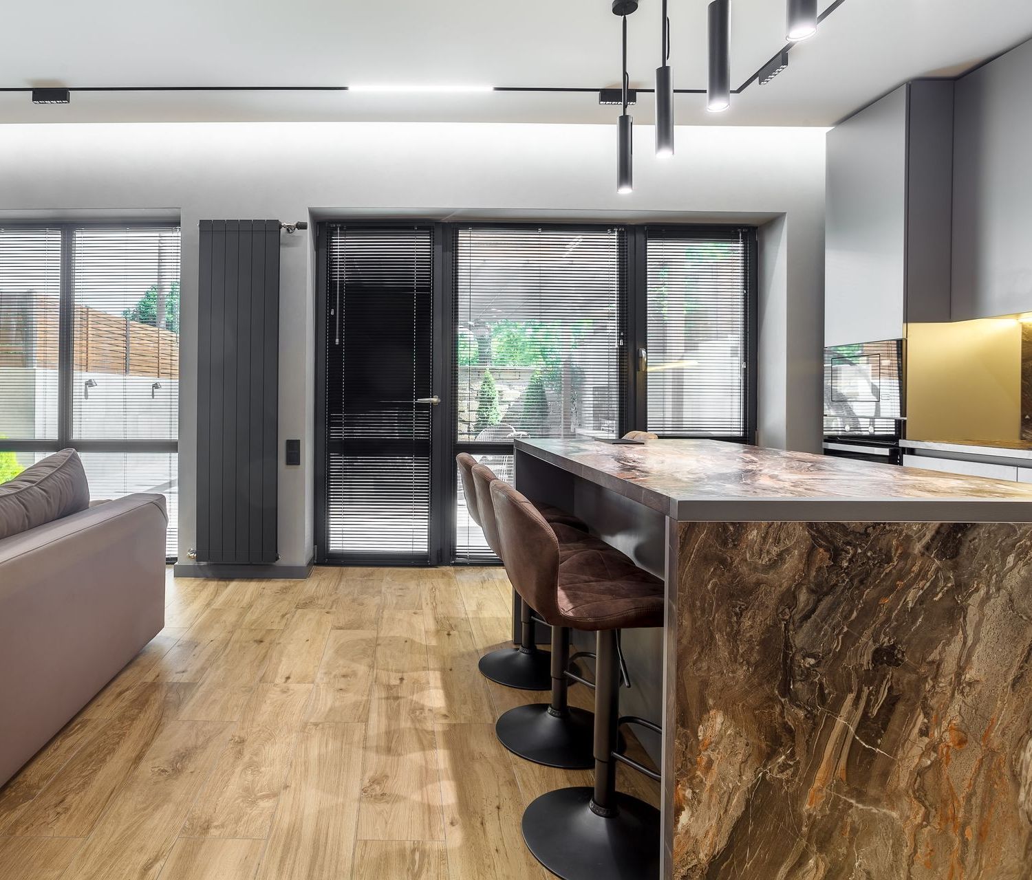 A living room with a couch and a kitchen with a bar and stools.