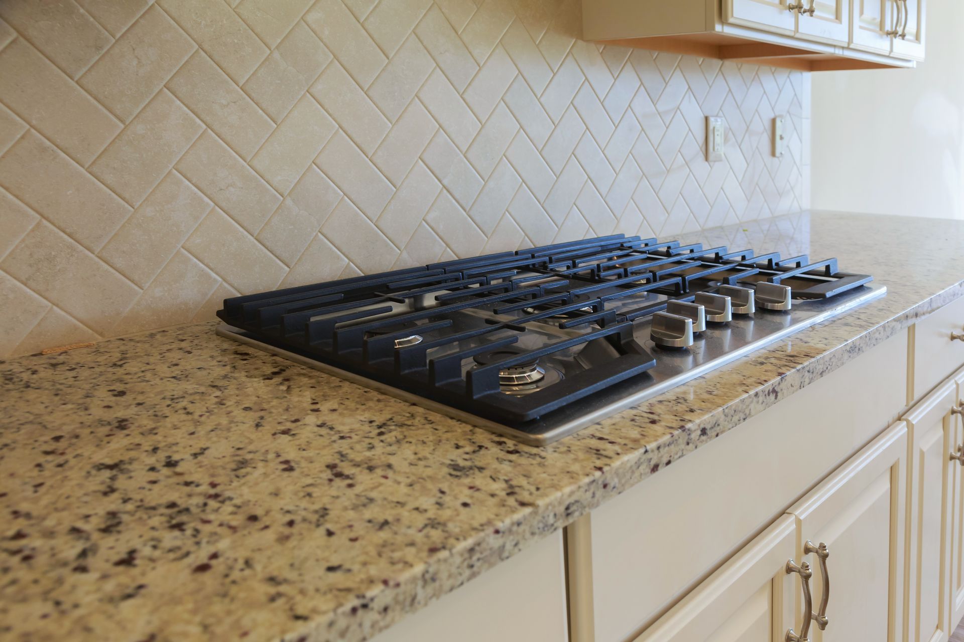 A stove top oven is sitting on top of a granite counter in a kitchen.