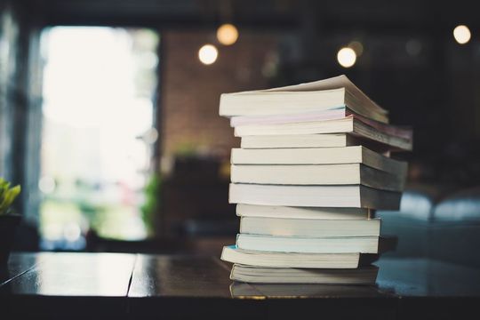 piles of books on table over blurred library background