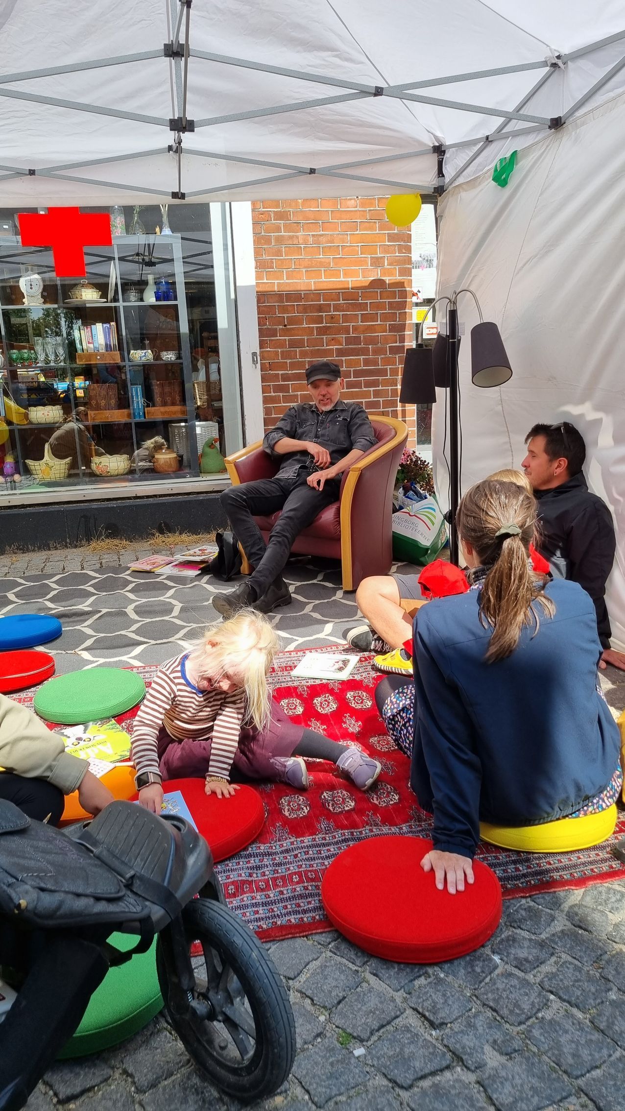 En gruppe mennesker sidder under et telt på jorden.